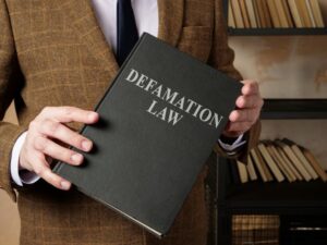 A lawyer in a suit holding a book titled "Defamation Law."