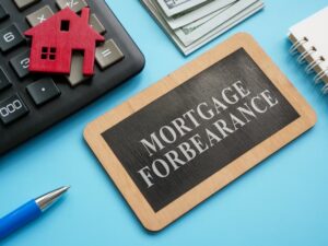 Wooden plate with inscription mortgage forbearance and model of house.