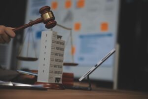 Real Estate Law, Home Insurance, property Tax, Auction and Bidding concepts. small toy house model with gavel justice hammer on desk in courthouse.