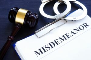 Judge's gavel, handcuffs and word misdemeanor written on a legal document