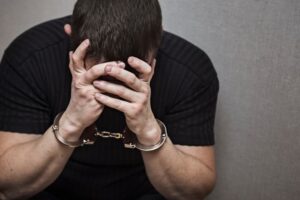 Criminal in handcuffs regrets the crime. Arrested man with handcuffs.