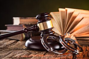 Judge's gavel, handcuffs and opened law book on the table