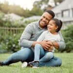 Smile, father and hug child on grass