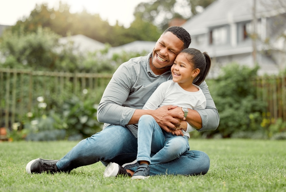 Smile, father and hug child on grass