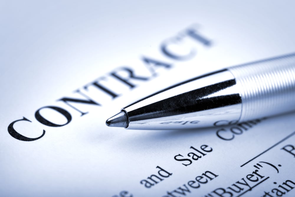 Close-up of a silver pen resting on a printed business contract.