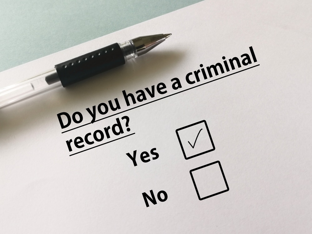 Paper form with “Do you have a criminal record?” and the “Yes” box checked.