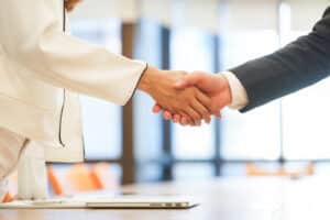 Two business professionals shaking hands after signing a contract.