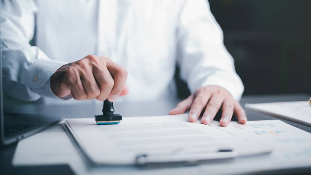 Person stamping a business contract document, symbolizing legal approval.