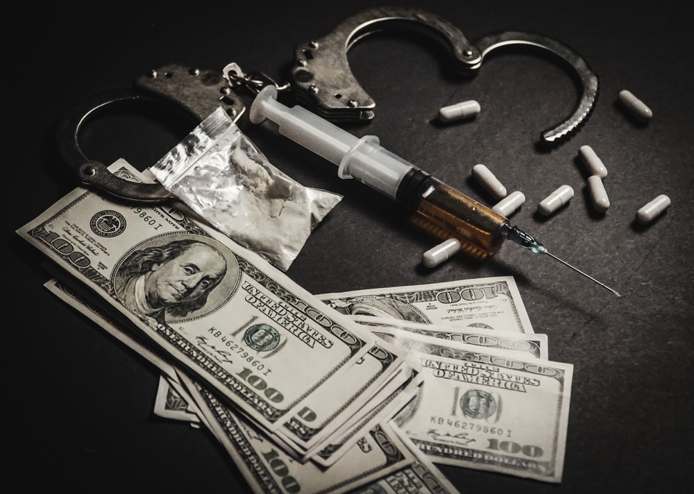 Handcuffs, syringe, drugs, and cash representing drug charges in Florida