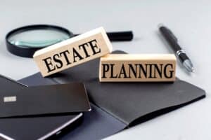 Wooden blocks reading “Estate Planning” on a desk with documents and pen