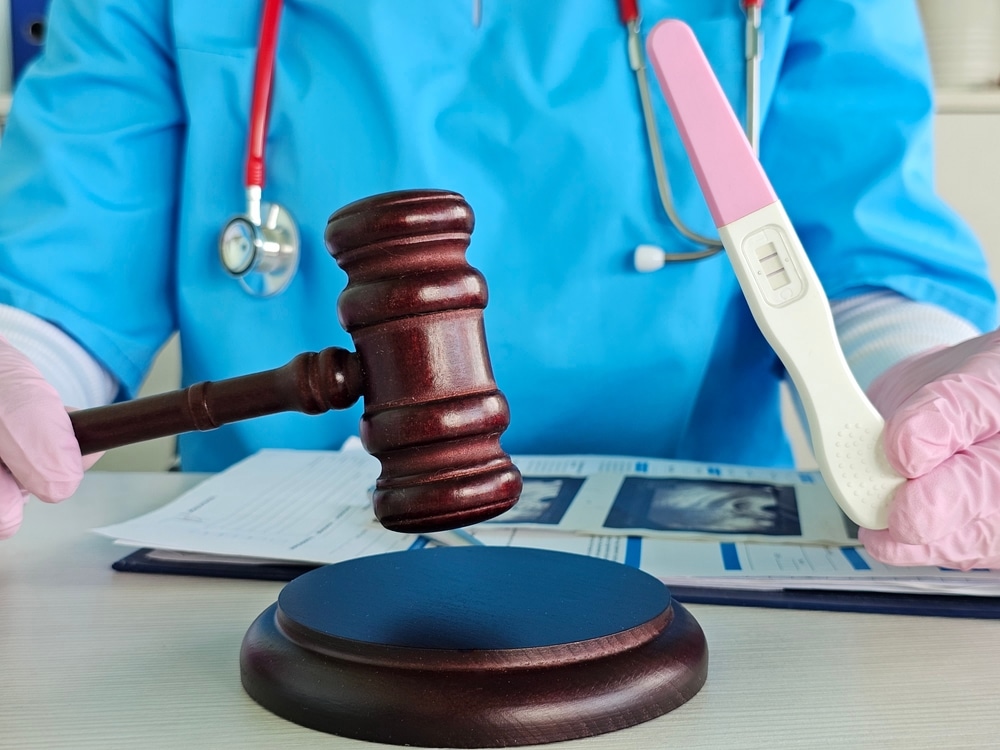 Doctor holding gavel and pregnancy test to represent court-ordered genetic testing in Florida paternity cases