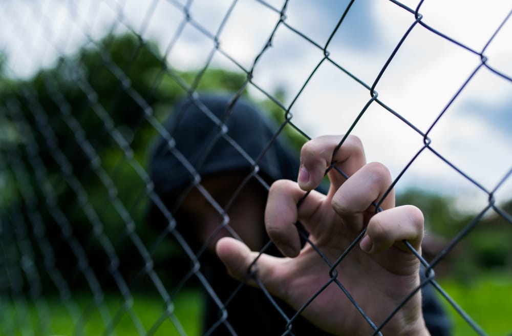 Teenager behind a chain-link fence, representing juvenile detention in Florida.