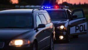 Law enforcement officer pulling over a car at dusk in Florida.