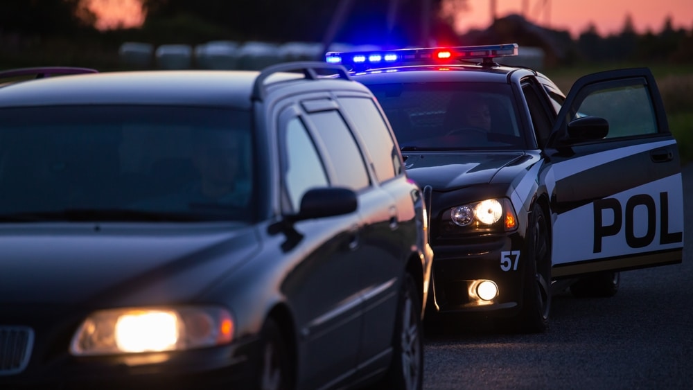 Law enforcement officer pulling over a car at dusk in Florida.