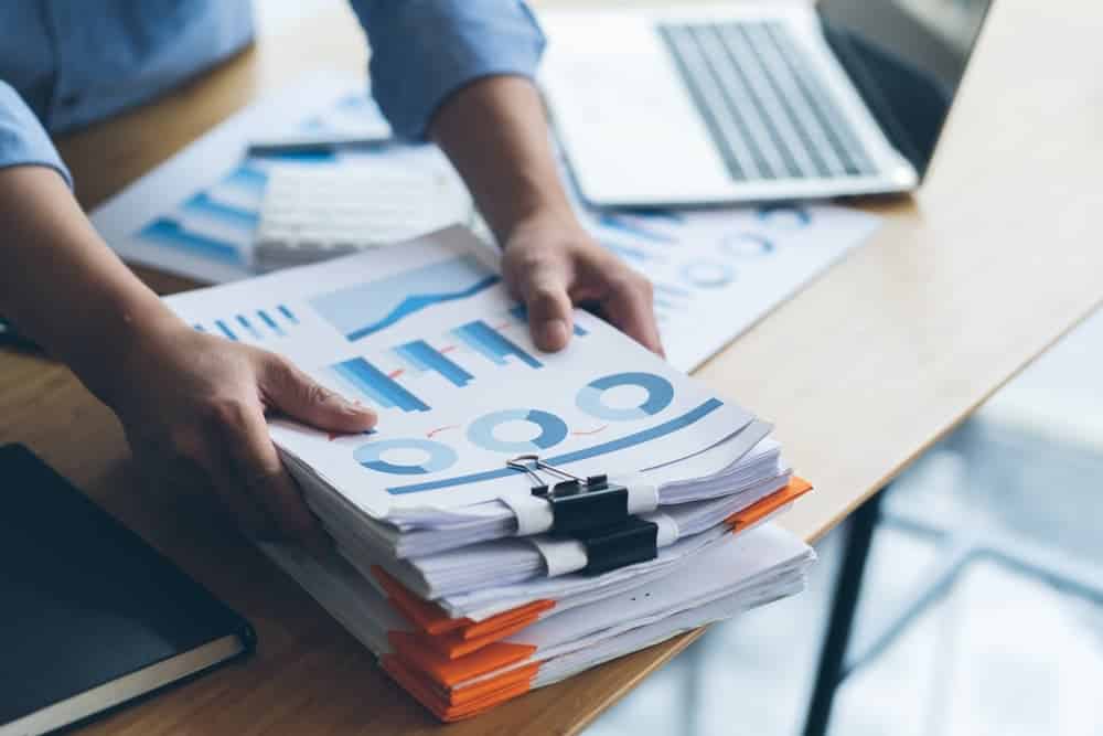 Businessman Preparing reports papers with graphs, charts on Stacks of documents files for finance in office