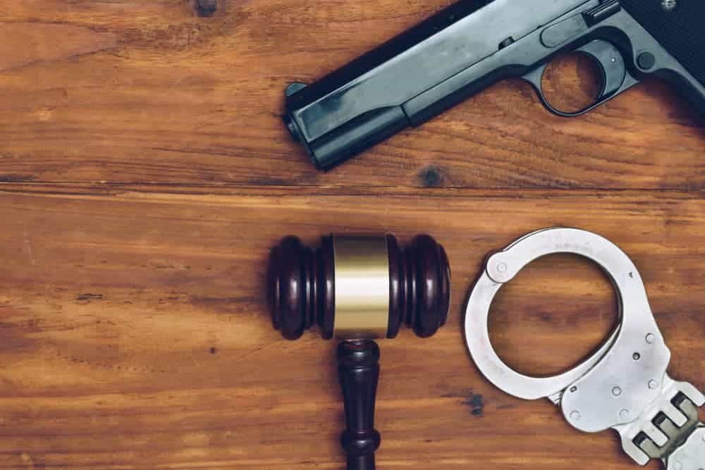 Judge gavel, handgun and handcuffs on wooden background