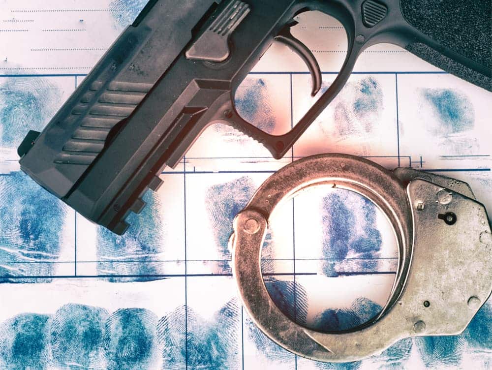 Gun and police handcuff on fingerprint crime page file. Crime and violence concept.